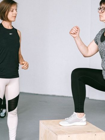 Fitness coach guides a woman in workout indoors. Focus on exercise and healthy lifestyle.