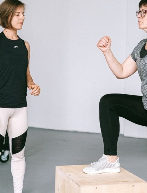 Fitness coach guides a woman in workout indoors. Focus on exercise and healthy lifestyle.